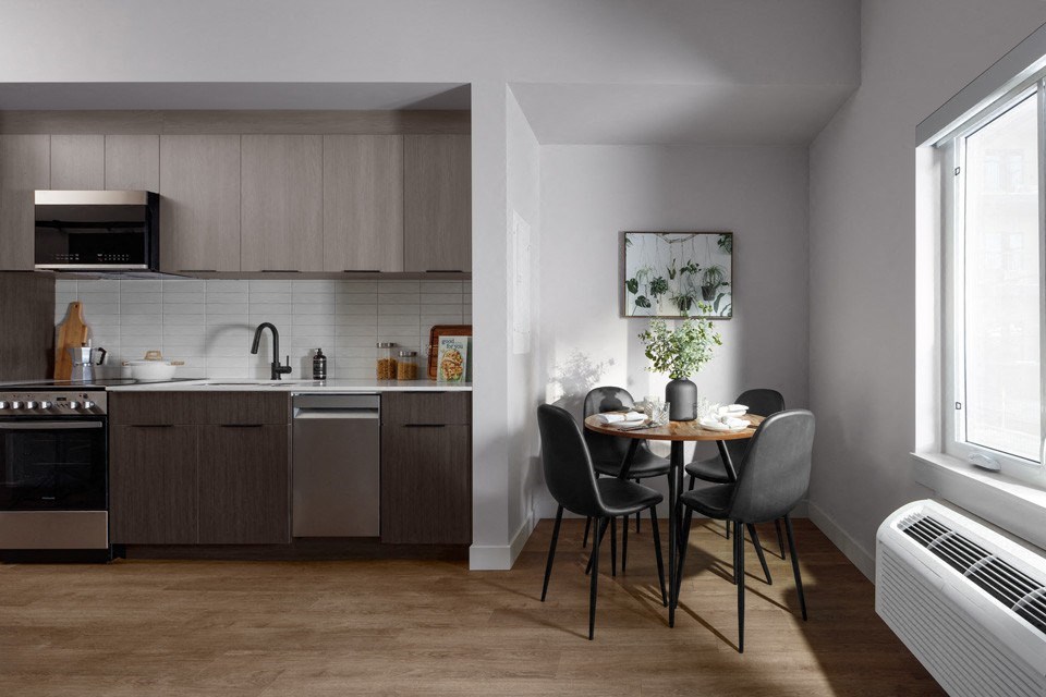 A modern kitchen with a dining table set for two at The Ambrosi in Kelowna, BC.