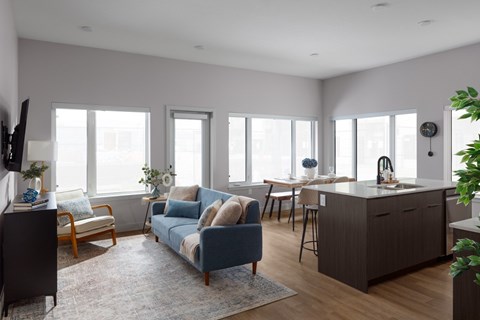 A living room with a blue couch and wooden floors.
