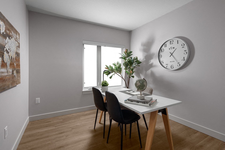 A room with a table, chairs, and a clock on the wall at The Ambrosi in Kelowna, BC.