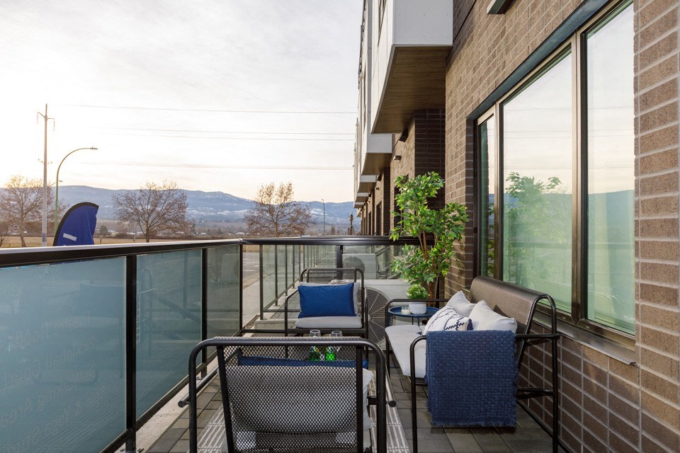 A balcony with a table and chairs overlooking a mountain range at The Ambrosi in Kelowna, BC.