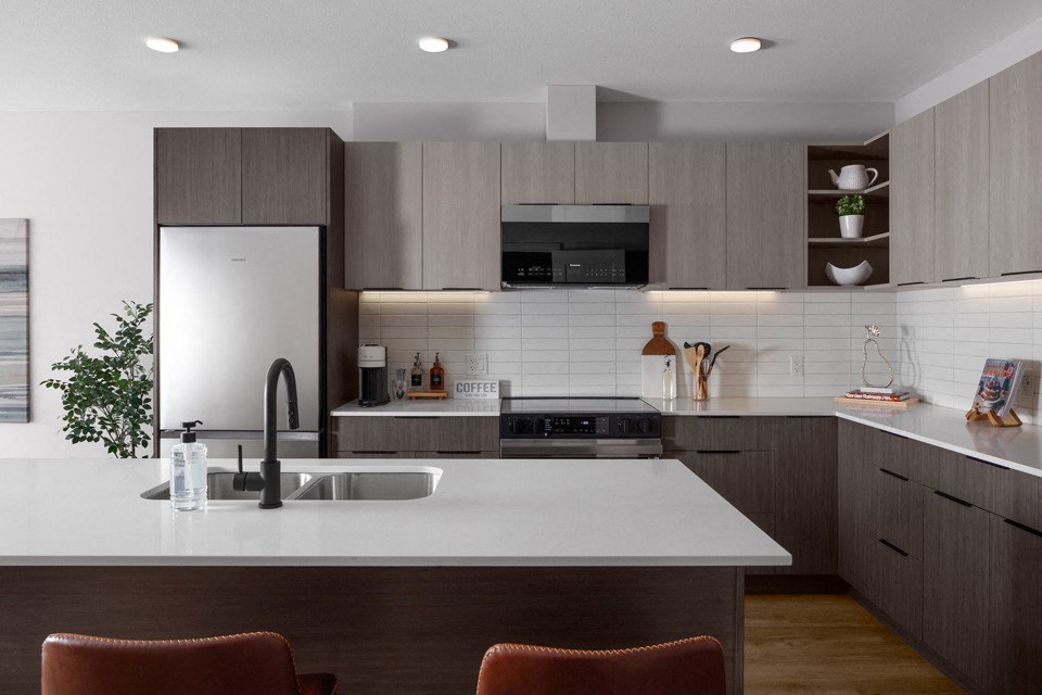 A modern kitchen with a white countertop and brown cabinets at The Ambrosi in Kelowna, BC.