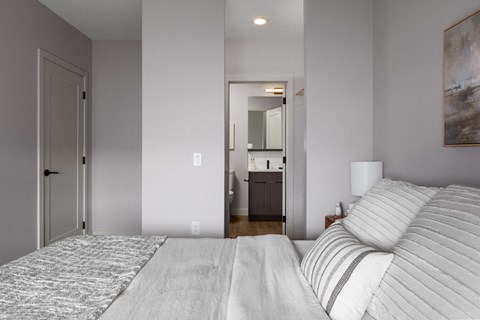 A bedroom with a large bed and a painting on the wall at The Ambrosi in Kelowna, BC.