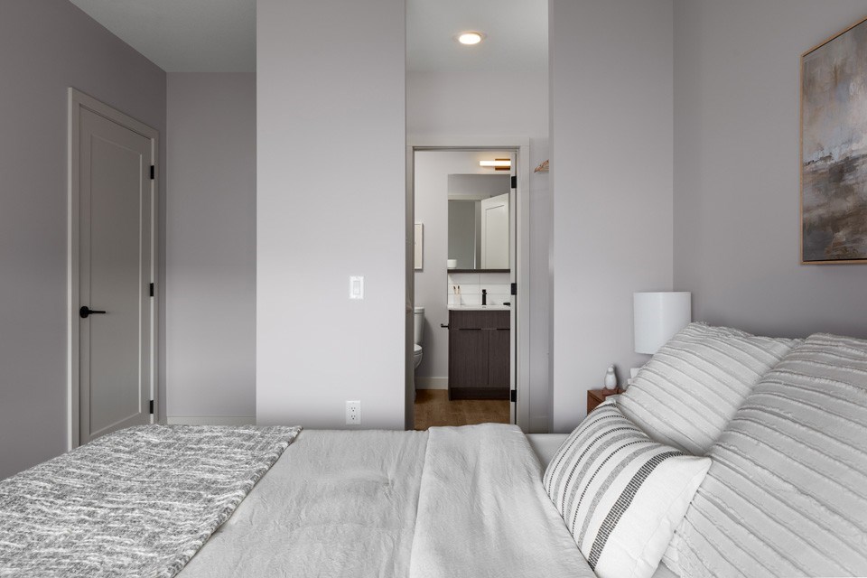 A bedroom with a large bed and a painting on the wall.