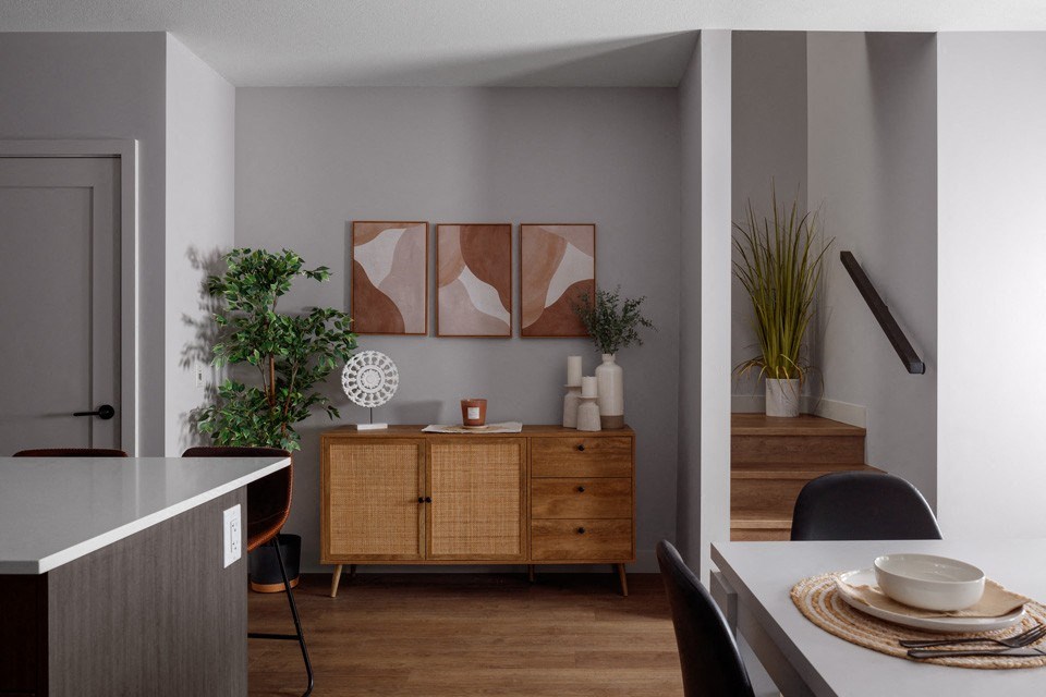 A modern kitchen with a wooden cabinet and a dining table set for two at The Ambrosi in Kelowna, BC.