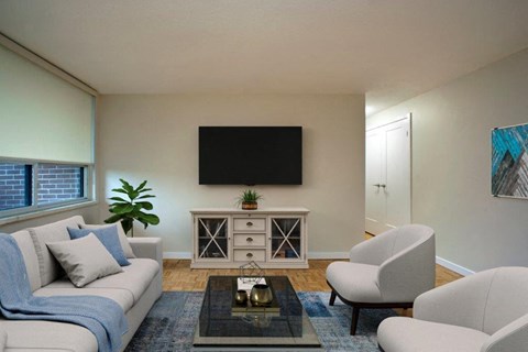 A living room with a grey couch, a coffee table, and a television on a cabinet.