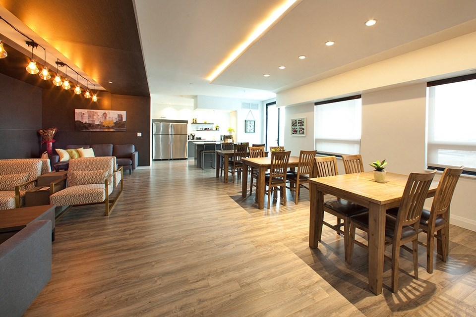 Penthouse resident's lounge with a large dining area with tables and chairs and a caterer's kitchen in the background at Trio on Belmont in Kitchener, ON