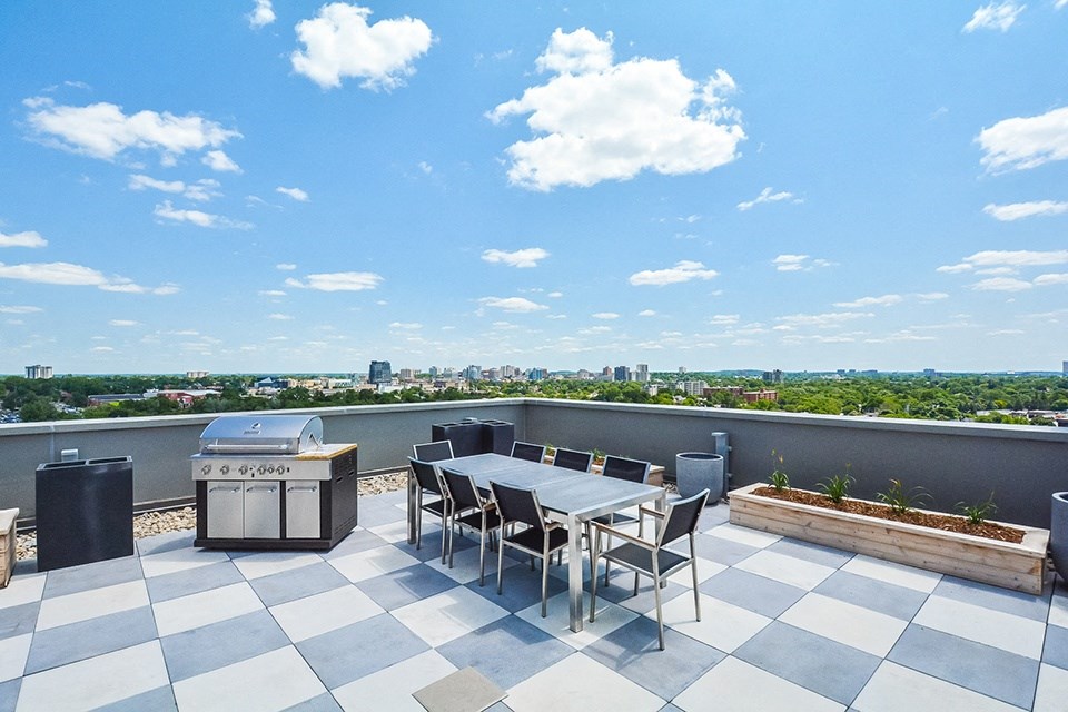 A rooftop patio with a BBQ grill and a table and chairs at Trio on Belmont in Kitchener, ON