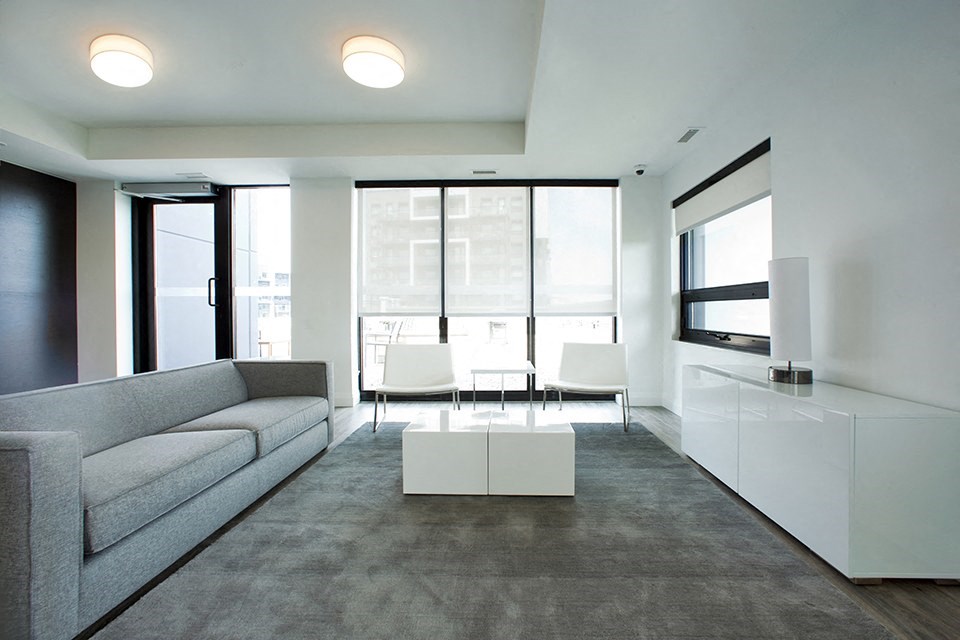 Lounge area with grey couch and white table in the social room located in Building C at Trio on Belmont in Kitchener, ON