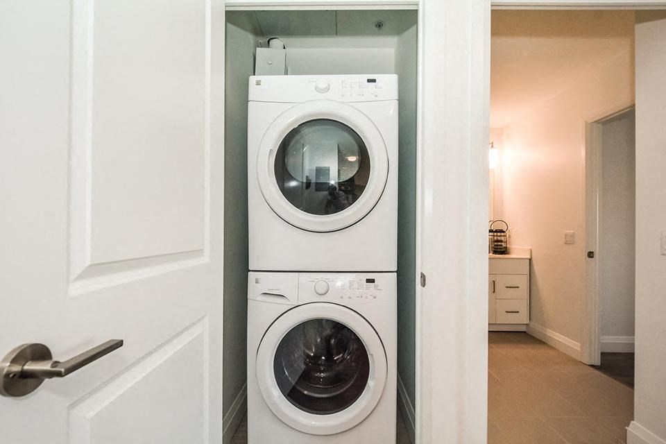 In-suite laundry with a white stacked washer and dryer in a 1 bed 1 bath variation B in building A at Trio on Belmont in Kitchener, ON