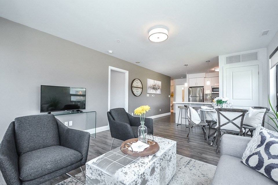 Open-concept living and dining area, looking towards kitchen, in a 2 bed + den 2 bath variation E in building A at Trio on Belmont in Kitchener, ON