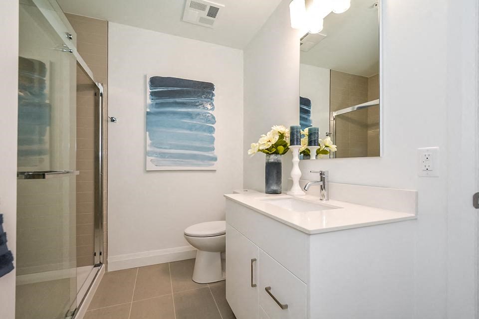 Primary bedroom ensuite bathroom with a walk-in shower, toilet and white vanity in a 2 bed + den 2 bath variation E in building A at Trio on Belmont in Kitchener, ON