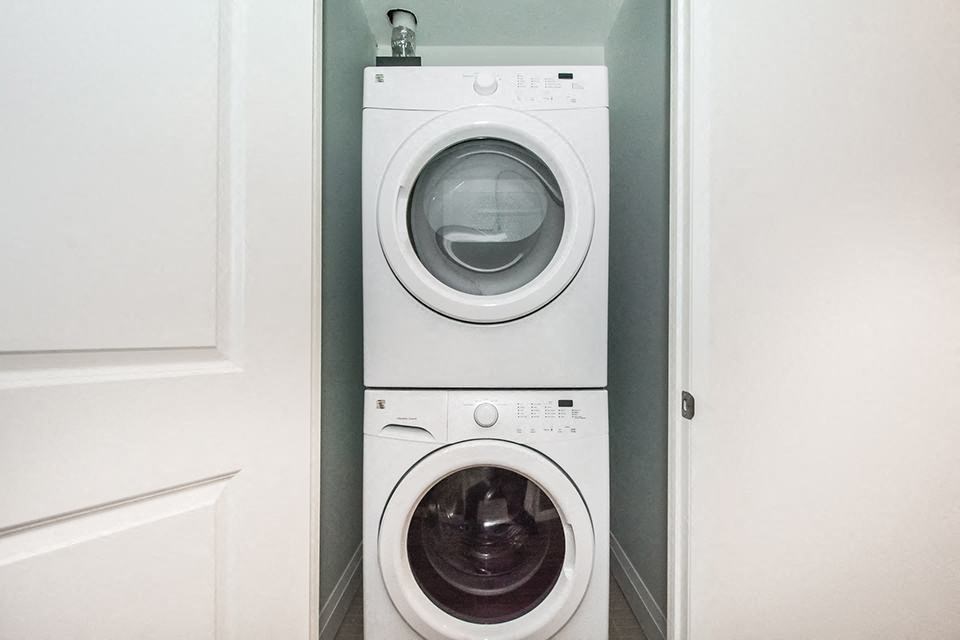 White stacked washer and dryer in-suite laundry in a 2 bed + den 2 bath variation E in building A at Trio on Belmont in Kitchener, ON