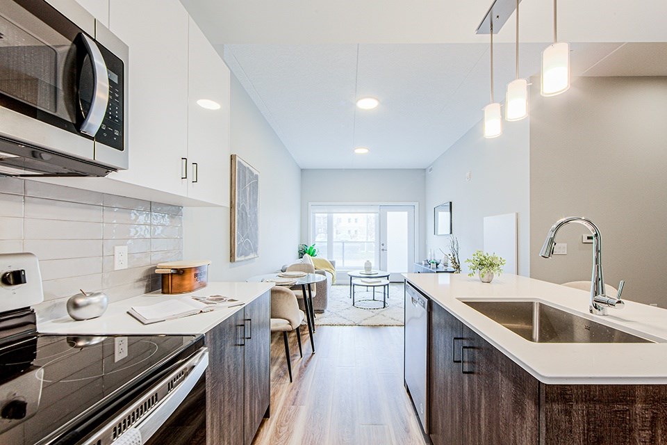 A modern kitchen with dark wood-look lower and white upper cabinets and stainless steel appliances in a 2 bedroom 2 bathroom variation C layout at Vale Station Apartments in Waterloo, Ontario