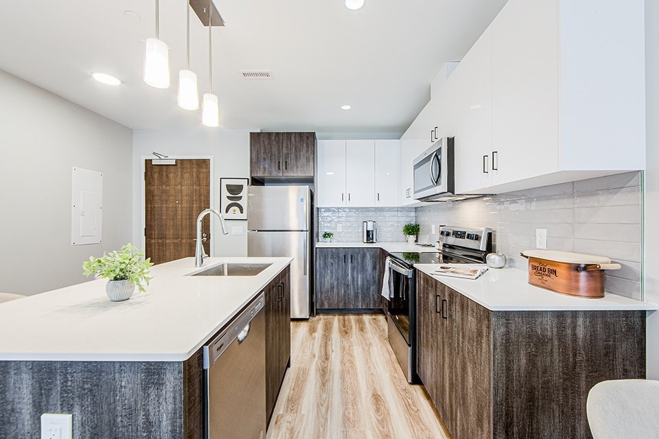 A modern kitchen with wood-look lower and white upper cabinets and a white countertop in a 2 bedroom 2 bathroom variation C layout at Vale Station Apartments in Waterloo, Ontario