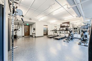 A spacious gym with a variety of equipment and an elevator that connects to a Yoga and Pilates studio on the floor above at Vale Station Apartments in Waterloo, Ontario.