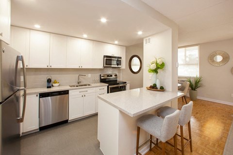 A kitchen with white cabinets and a white island with a counter.