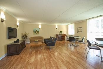 social room with tables, chairs, sofa and TV at Valleyview Apartments in Newmarket ON