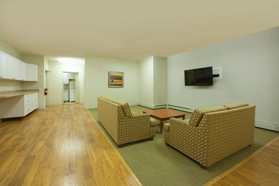 Social room with couches and TV at Hillcrest Terrace in St. Catharines, ON