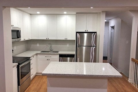 a kitchen with white cabinets and a stainless steel refrigerator