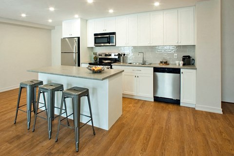 A kitchen with white cabinets and a wooden floor.