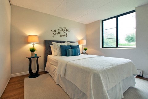 A bedroom with a white bed and two lamps.
