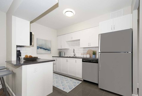 A modern kitchen with white cabinets and a grey refrigerator.