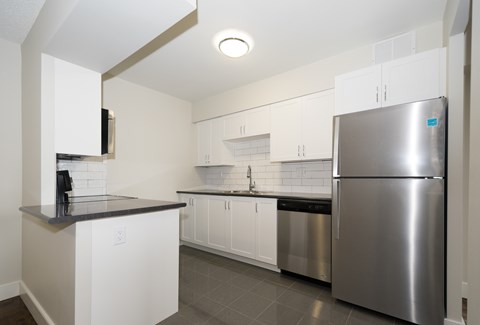 A kitchen with a stainless steel refrigerator and white cabinets.