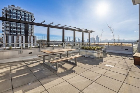A sunny rooftop patio with a table and benches.