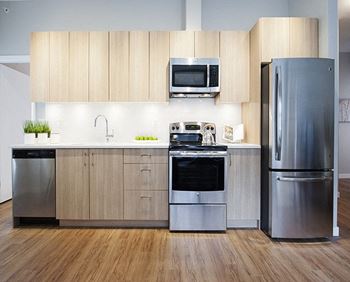 a kitchen with wooden cabinets and stainless steel appliances at Yello On Yates in  Victoria, BC