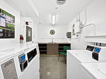 A white colored room with a washing machine and a microwave.