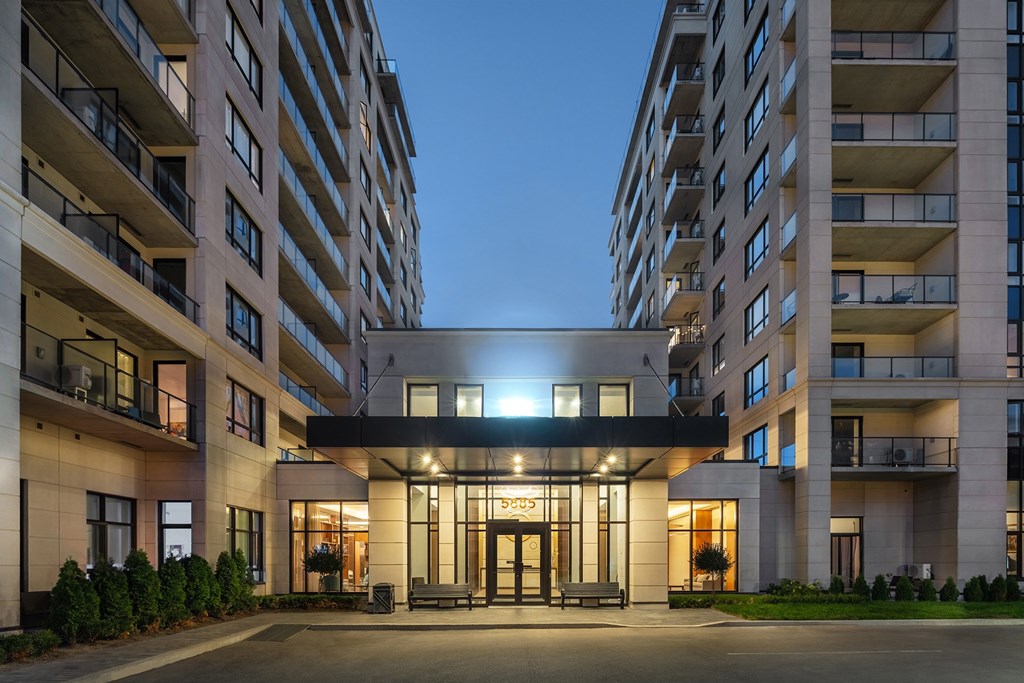 A modern building with a lit entrance and balconies on the side.