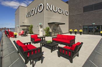 a patio with red chairs and tables in front of a building