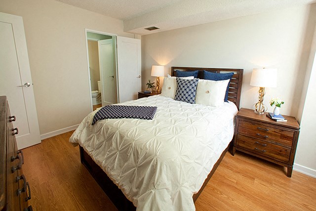 Enjoy cozy living in bedrooms with generous city views Edgehill Apartments in Barrie, ON Bedroom with neatly made bed and two nightstands that have two lamps on ether side