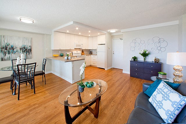 Edgehill Apartments in Barrie, ON Open concept room with sleek dinner table, kitchen, coffee table, couch and drawers.
