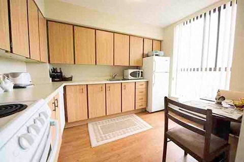 A kitchen with wooden cabinets and a white stove.