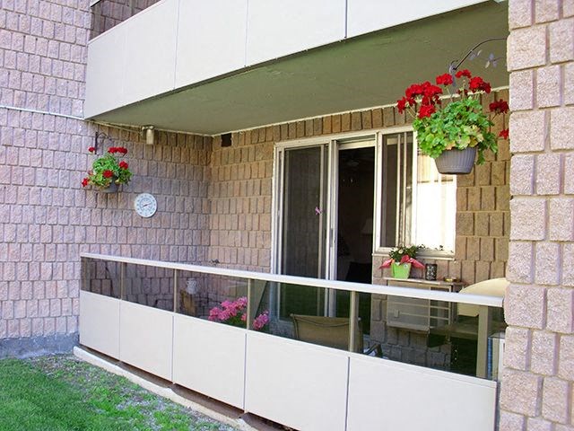 Cozy grounded patio with flower pots hanging from the ceiling Backyard with BBQ and tables and chairs at Bradford Place Apartments in Bradford, ON