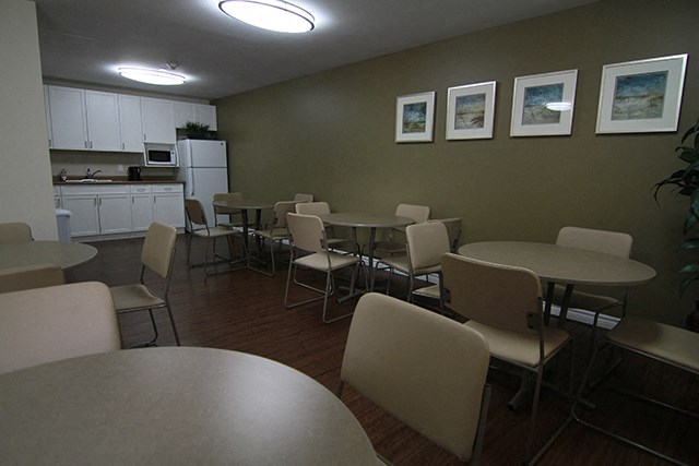Cedarpoint Apartments in Cambridge, ON social room with tables, chairs and kitchen