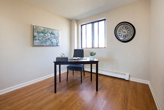 Mountain View Room with dark wood study desk. A clock and painting hang on the wall next to a window in Collingwood, ON