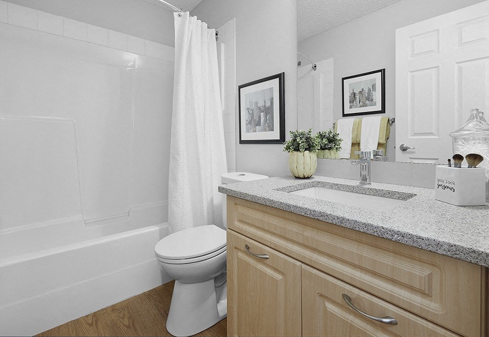 A white toilet sits in a bathroom next to a bathtub.