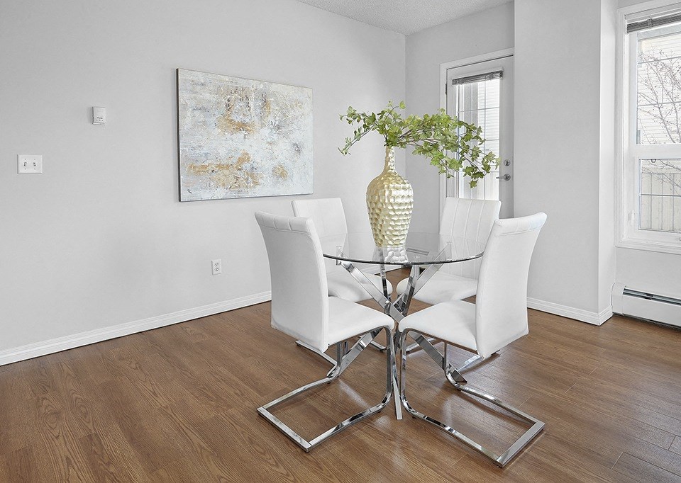 A glass dining table with a vase and two chairs.