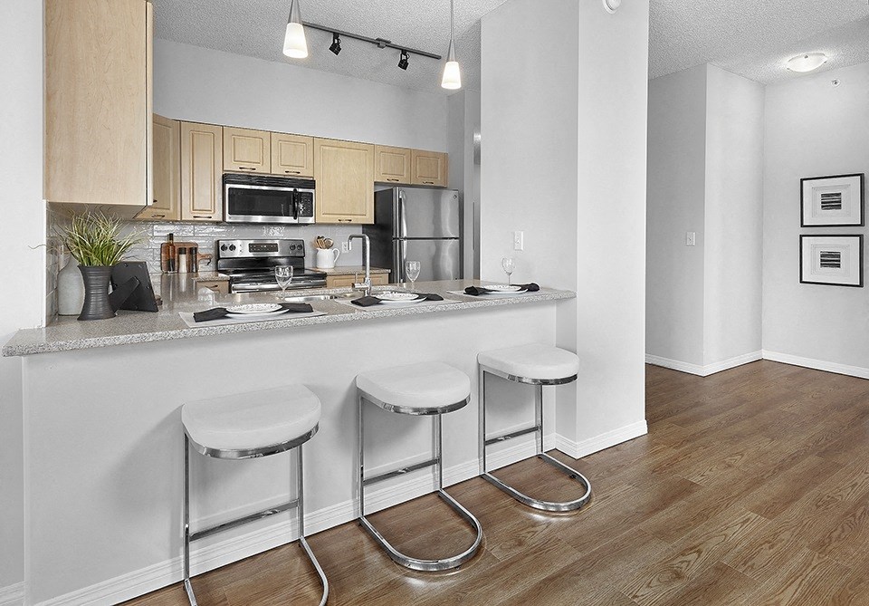 A kitchen with a white countertop and bar stools.
