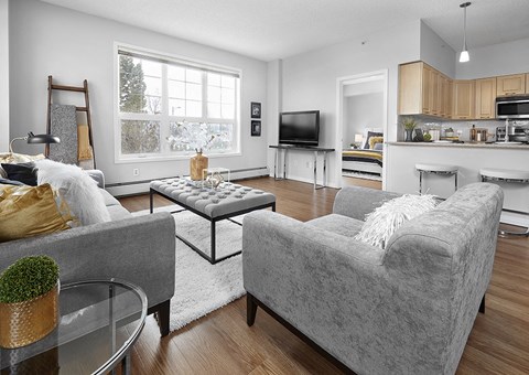 A grey couch sits in a living room with a glass table in front of it.