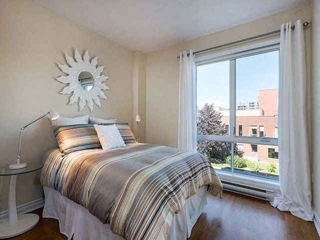 Excelsior Apartments bedroom with large window and hardwood flooring in Montreal, QC