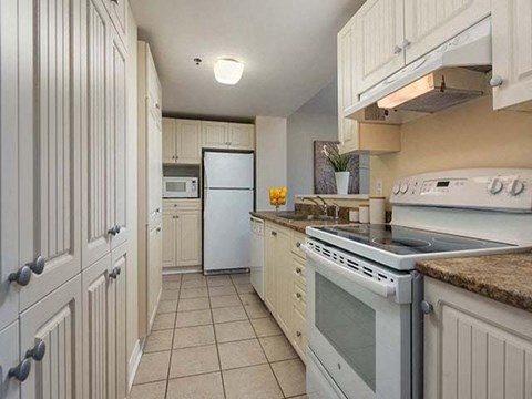 A kitchen with white cabinets and appliances.