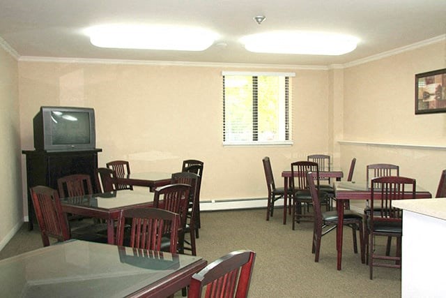 Common area with 5 tables surrounded by chairs. There's a TV on the left.