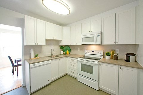 A kitchen with white cabinets and appliances.