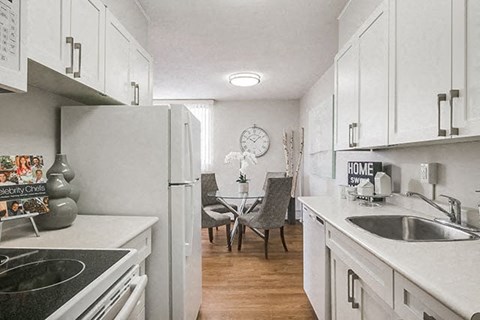 Victoria Place kitchen with white cabinetry, full range stove, and full size fridge in Saskatoon, SK