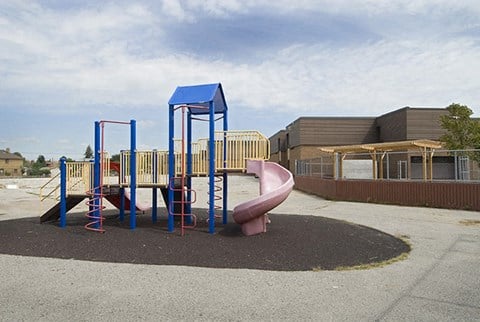 a playground with a pink slide and blue playset