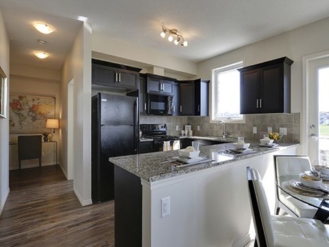 Feel like a chef in luxury style kitchen and dining areas Airdrie Place in Airdrie, AB Open concept kitchen-dining area lit by sunlight