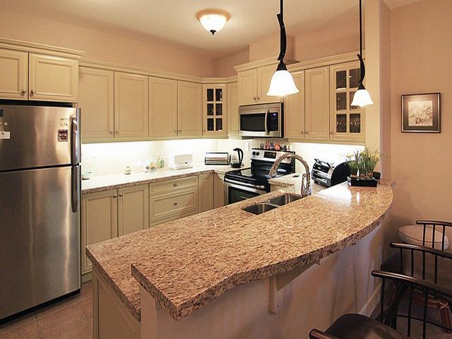 The Conservatory beautiful kitchen with white cabinetry and stainless steel appliances in Kelowna, BC